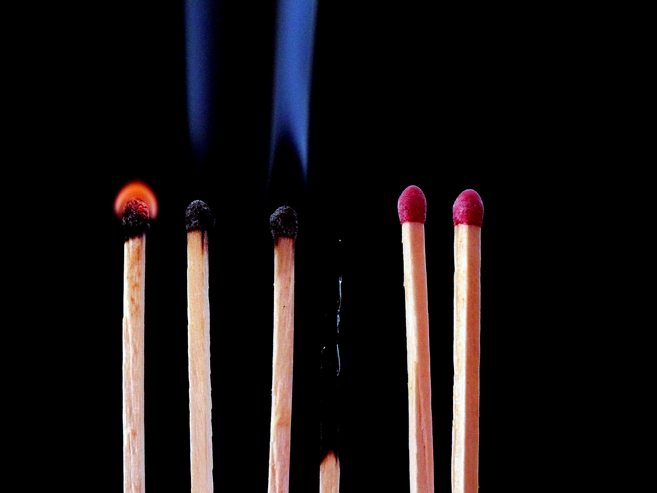Several matches, one starting to catch fire, two smoking, one burnt to cinders, two unlit
